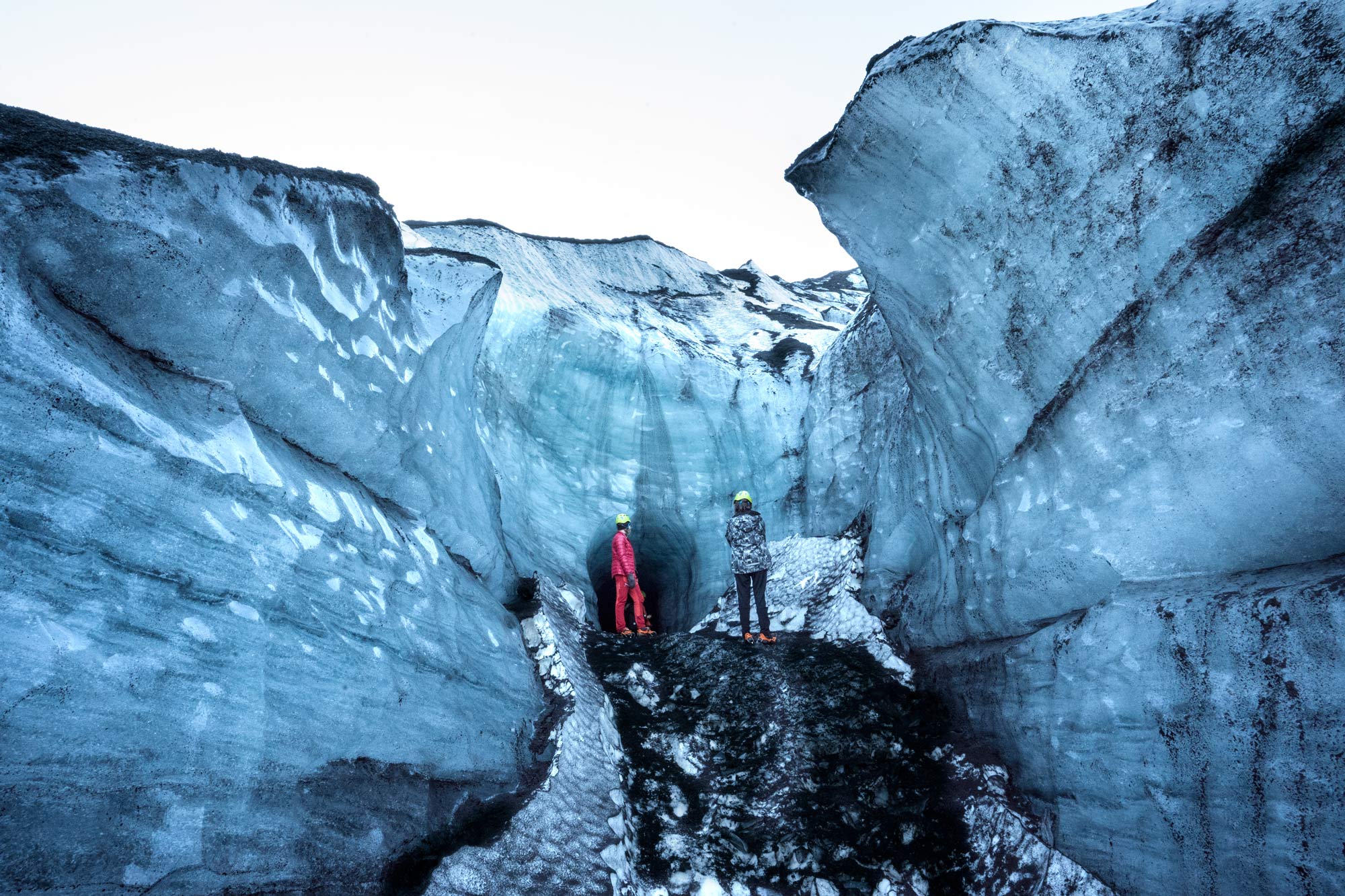 Hikers walking through a narrow glacial passage on Katla Glacier.