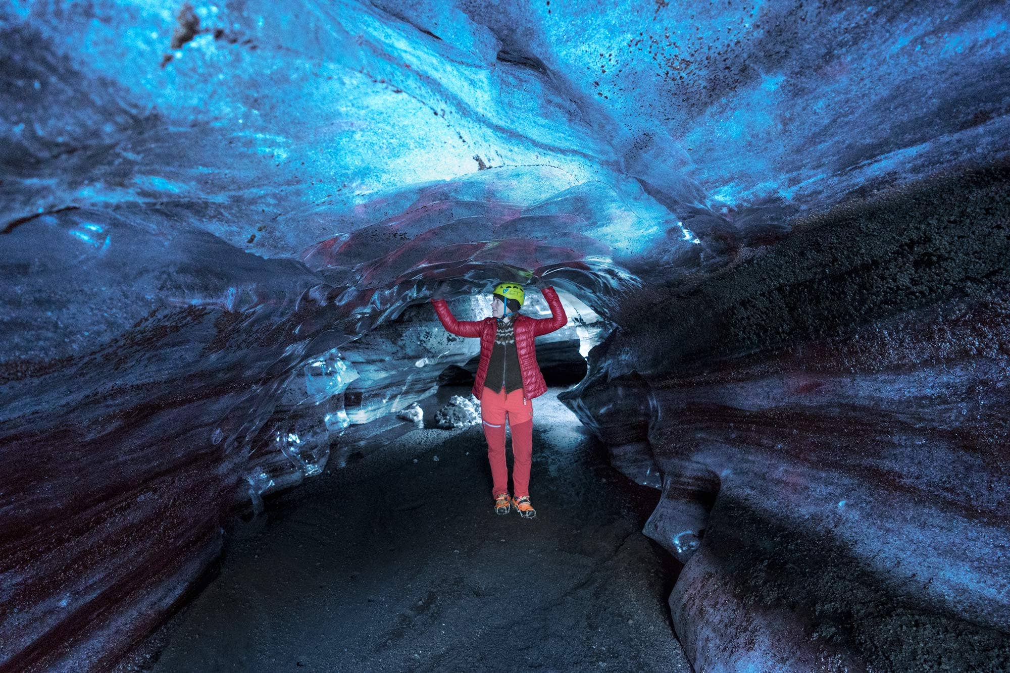 A visitor explores the Katla ice cave, standing amidst striking blue ice.