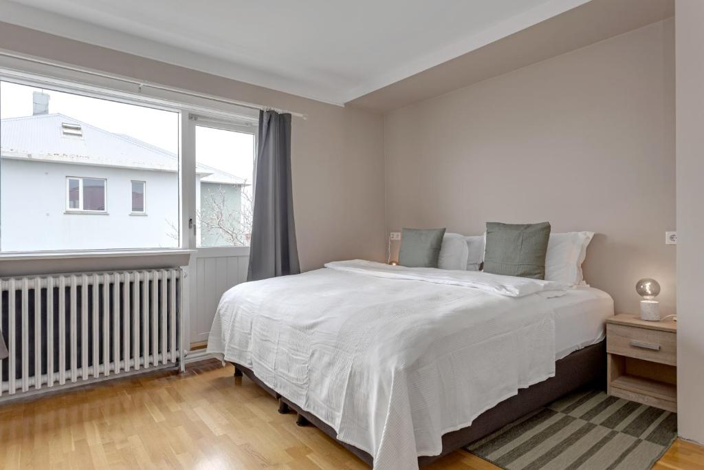 Habitación amplia con cama doble situada junto a una gran ventana lateral que llena la estancia de luz natural en Audur by Guesthouse Reykjavik.