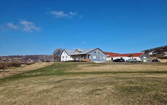 Svansholl Apartments under a clear blue sky with wide grassy fields in front.