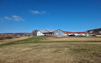 Svansholl Apartments under a clear blue sky with wide grassy fields in front.
