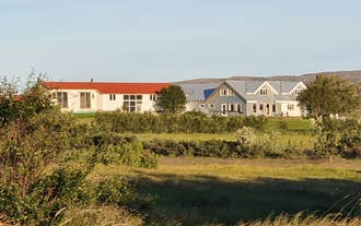 Svansholl公寓乡村物业，白色建筑配红色和蓝色屋顶，周围环绕绿地和开阔草场。