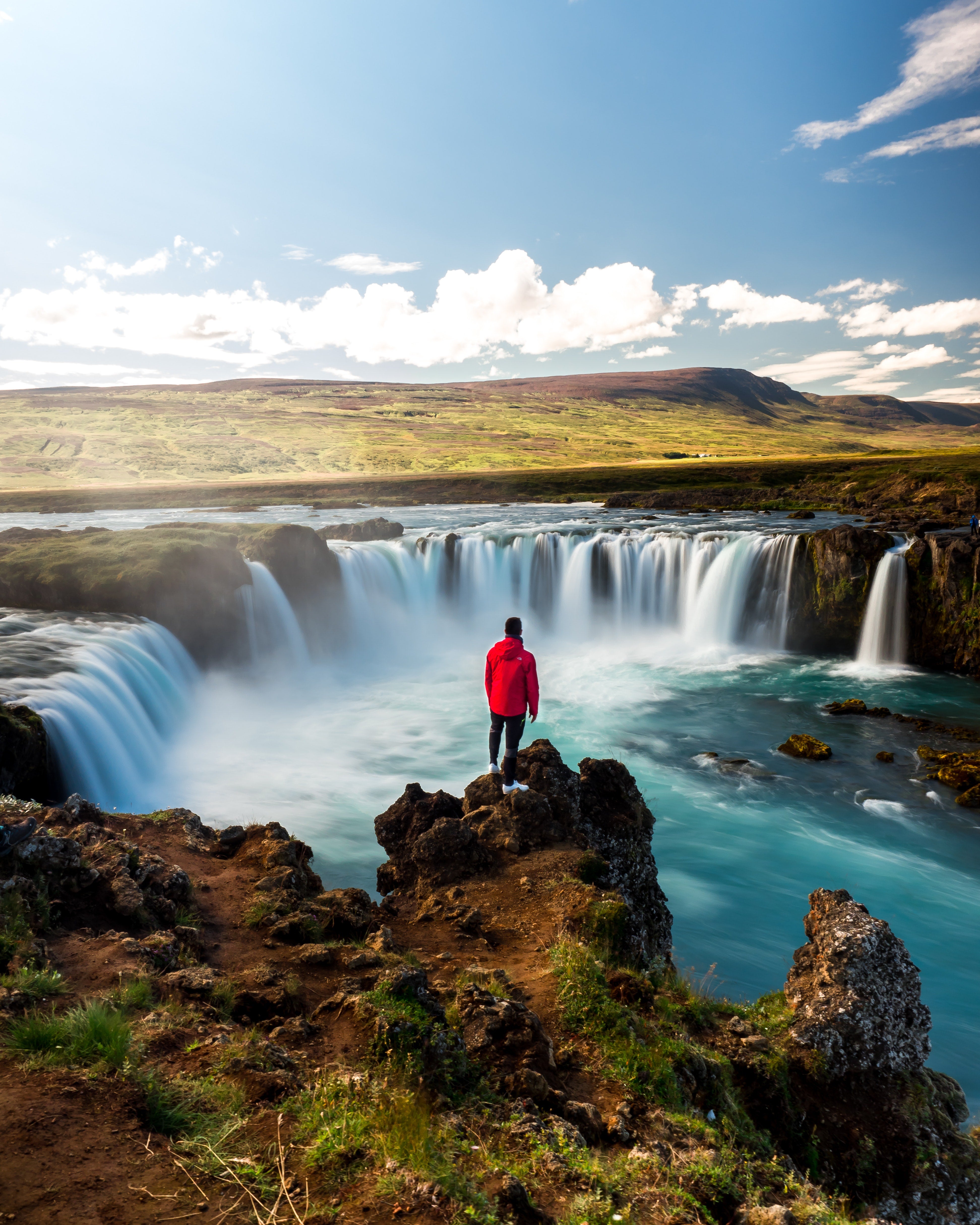 A traveler looks out over Godafoss Waterfall in North Iceland.