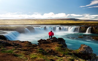 A traveler looks out over Godafoss Waterfall in North Iceland.
