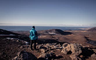 Hiker overlooking the volcanic landscape and Atlantic Ocean on the Reykjanes Peninsula, Iceland.