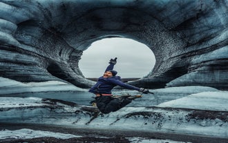A traveler jumps joyfully at the Katla Ice Cave in Iceland.