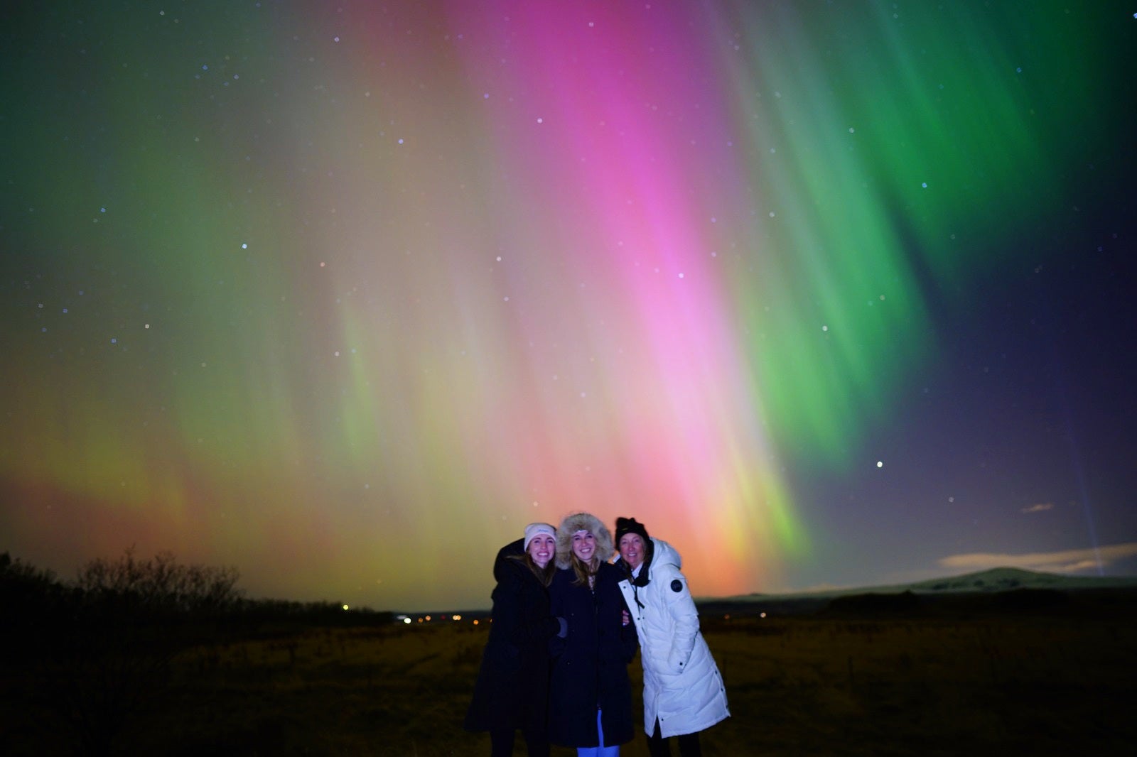 Friends smiling under the auroras on a Reykjavik northern lights tour