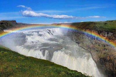 Gullfoss Waterfall with a rainbow shooting from its heavy mist.