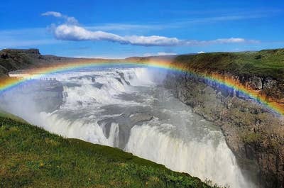 Wodospad Gullfoss z tęczą wyłaniającą się z gęstej mgły.