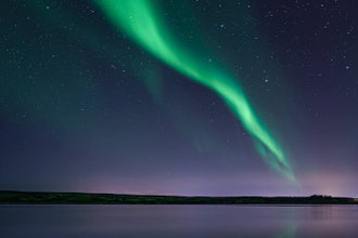 The northern lights in the sky above a body of water.