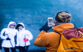 Two tourists pose for a photo in an ice cave on solheimajokull Glacier while another tourist snaps the photo for them.