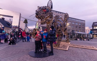 People on a walking tour of Reykjavik pose in front of a Christmas cat sculpture.