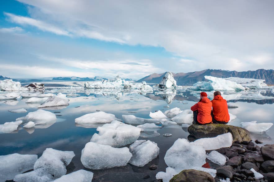 Two travelers sitting by the icebergs at Jokulsarlon Two travelers sitting by the icebergs at Jokulsarlon