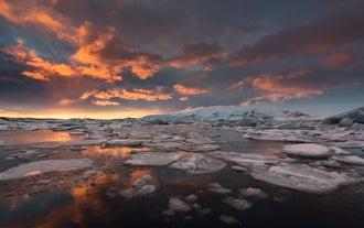 Le coucher de soleil se reflète sur les eaux glacées de la lagune glaciaire de Jokulsarlon, avec des icebergs flottants sous un ciel spectaculaire.