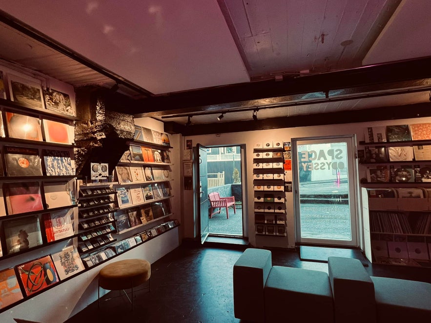 Interior of Space Odyssey record store in Reykjavík with shelves of vinyl, tapes, and zines, warm lighting, and a view of the street through the door. Interior of Space Odyssey record store in Reykjavík with shelves of vinyl, tapes, and zines, warm lighting, and a view of the street through the door.