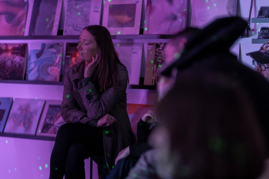 People attending a listening session at Space Odyssey in Reykjavík, with purple lighting and vinyl records on display in the background.