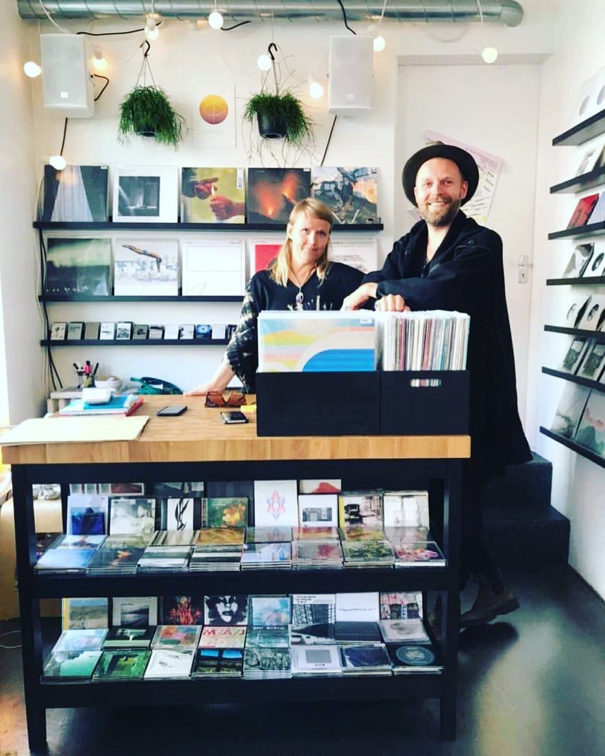 Pan Thorarensen and Gudrun Larusdottir standing behind the counter at Space Odyssey in Reykjavík, surrounded by vinyl records, CDs, and cassette tapes.