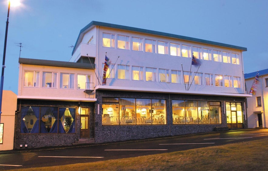 Hotel in Heimaey, South Iceland, with large front windows and glowing interior lights during blue hour on the Westman Islands.