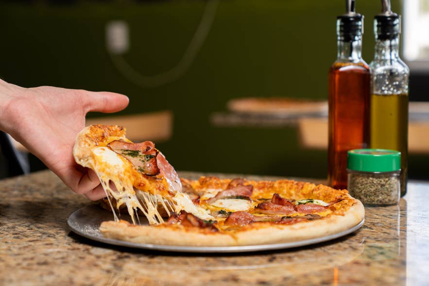 A person getting a slice of pizza at Daddi’s Pizza by Lake Myvatn in North Iceland