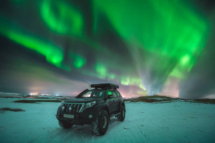 5 days in Iceland road trip with a jeep parked under the glowing northern lights in the Arctic sky.