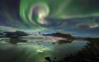 Noorderlicht dansend boven een gletsjerlagune in IJsland op een heldere winternacht.