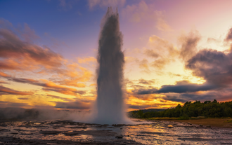 El géiser Strokkur entra en erupción al atardecer en el área geotérmica de Geysir, parte de la icónica ruta del Círculo Dorado en Islandia.