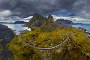 Flyfoto av Eystrahorn-fjellet og kystveien på Stokksnes-halvøya sørøst på Island under en dramatisk himmel.