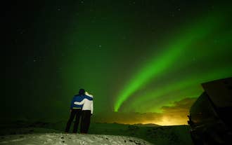 A pair of travelers share a special moment under the aurora in Iceland.
