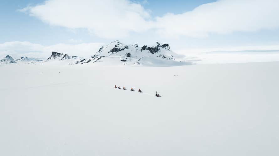 A line of snowmobile riders traverse the glacier near Reykjavik.