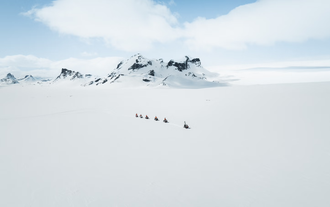 A line of snowmobile riders traverse the glacier near Reykjavik.