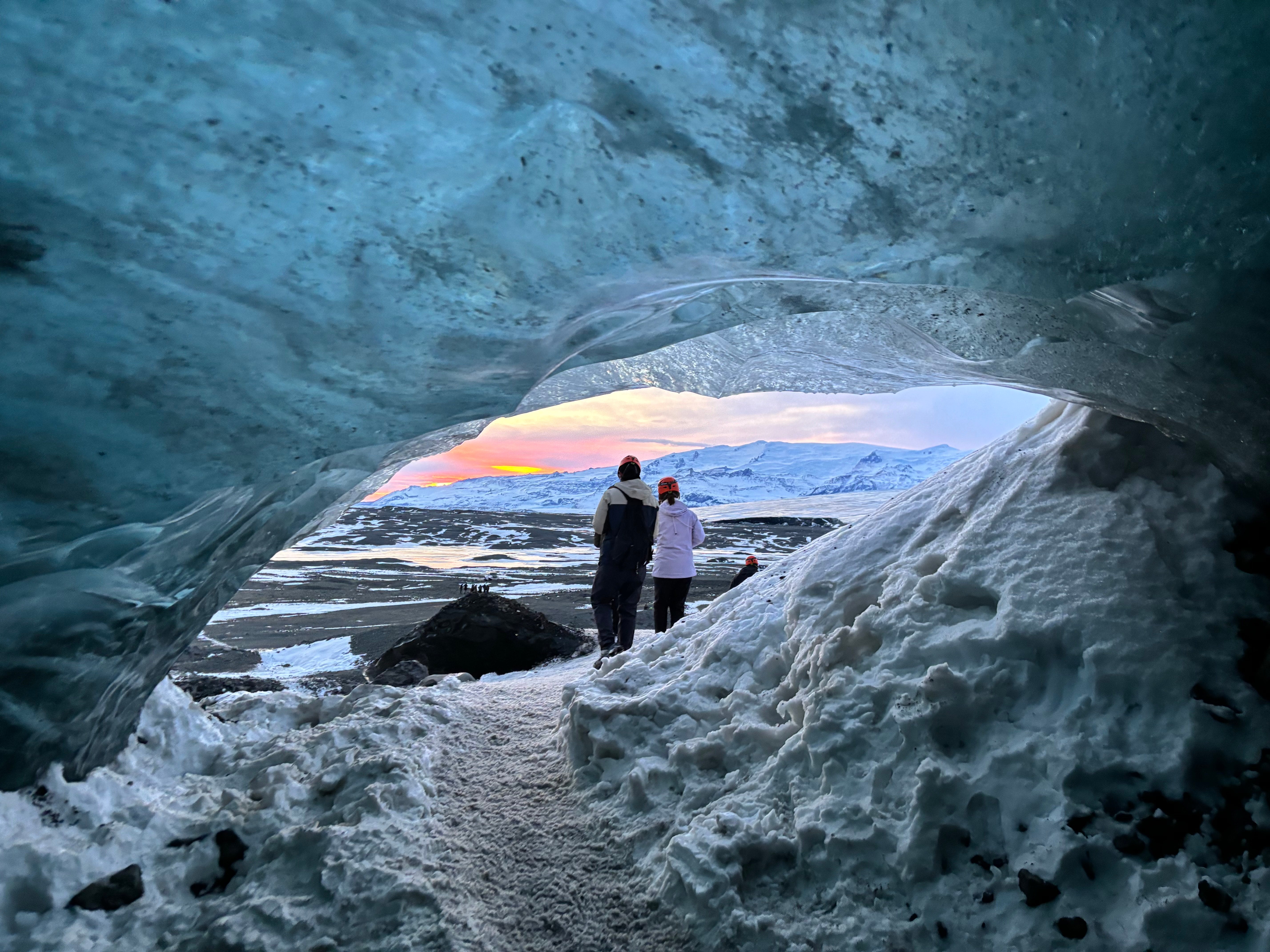 Una coppia si gode la vista del tramonto dalla grotta di ghiaccio cristallino