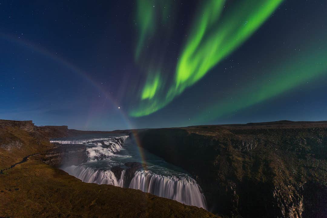 Nordlyset skinner over Gullfoss i Islands Gylne Sirkel, med en regnbue i tåken.