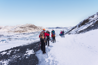 A group of travelers glacier hiking on the icy landscape of Solheimajokull.