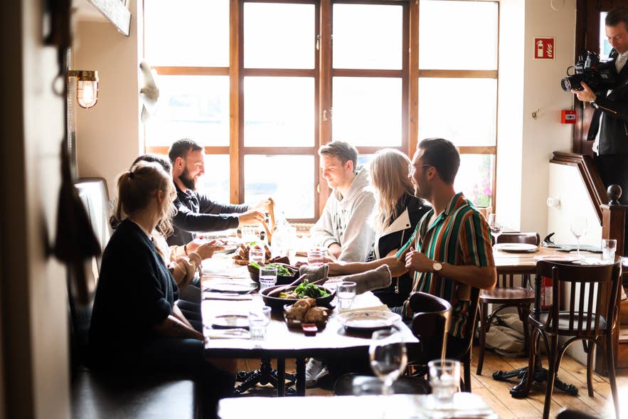 A group of travelers sharing a meal at a long table on the Akureyri food walk in North Iceland.