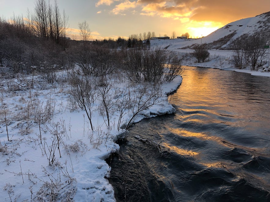 The snow-filled Ellidaa River during sunset in Ellidaardalur Valley in Reykjavik, Iceland.