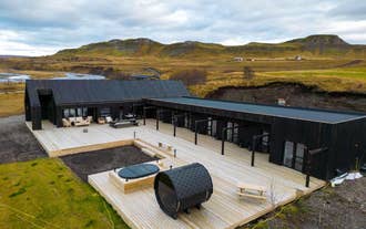 Exterior view of Studlastrengur – Luxury Private Villa with a large wooden deck, hot tub, and scenic landscape in the background