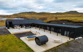 Exterior view of Studlastrengur – Luxury Private Villa with a large wooden deck, hot tub, and scenic landscape in the background