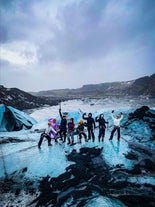 A group pose on the ice of Solheimajokull glacier during a glacier hiking tour in Iceland.