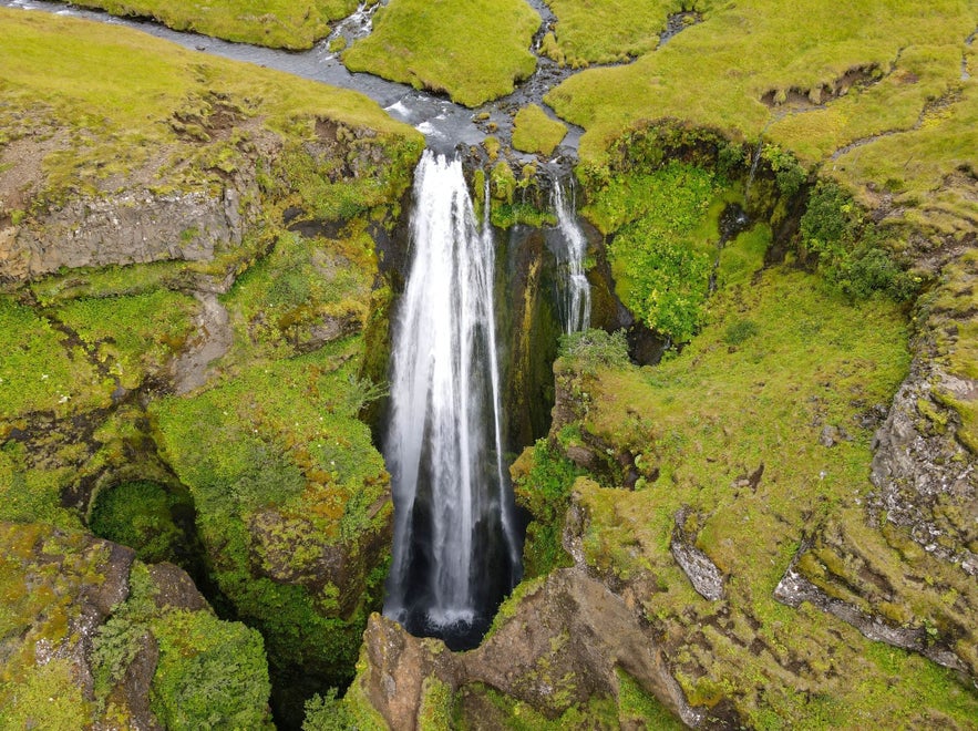 Gljufrabui Waterfall flowing through a mossy canyon in Iceland, seen from above in summer.