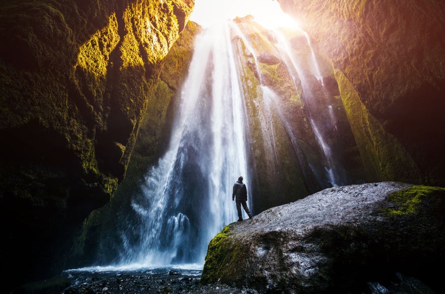 Gljufrabui Waterfall in Iceland cascading inside a moss-covered canyon, with a person standing on a wet rock. Gljufrabui Waterfall in Iceland cascading inside a moss-covered canyon, with a person standing on a wet rock.