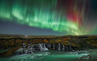 Nordlys glimter over Hraunfossar-vandfaldet i det vestlige Island på en klar vinteraften.