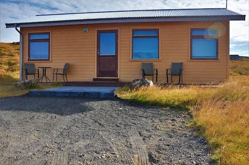 Close-up front exterior view of Fossatun Sunset Cottage with a table and chairs on the patio.