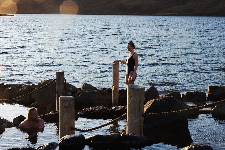 Travelers soaking in geothermal pools of Hvammsvik Hot Springs in Iceland.