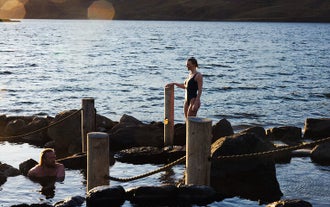 Travelers soaking in geothermal pools of Hvammsvik Hot Springs in Iceland.