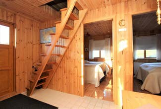 Interno della cabina rivestito in legno con scala ripida per il soppalco, pavimento piastrellato e camera accogliente illuminata dalla luce del sole.