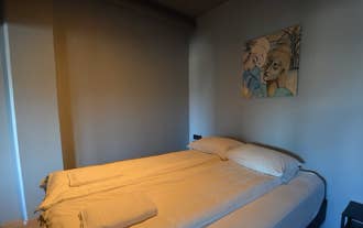 A neatly made double bed with two pillows, a framed picture above, and a nightstand with a lamp on each side.