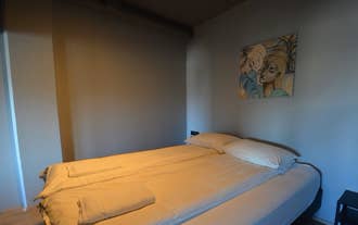 A neatly made double bed with two pillows, a framed picture above, and a nightstand with a lamp on each side.