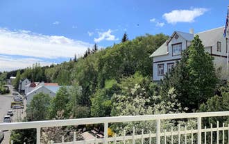 View of green trees and hills from a balcony with a white railing on a clear day.