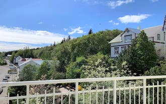 View of green trees and hills from a balcony with a white railing on a clear day.