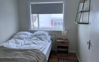 Cozy bedroom with a double bed, wooden nightstand, table lamp, and large window at M116 Historic Akureyri Apartments.